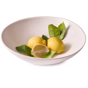 Perfect Hideaways: A matte white ceramic serving bowl holding whole and halved lemons with fresh green leaves, styled simply for a fresh, natural look. Perfect Hideaways shop