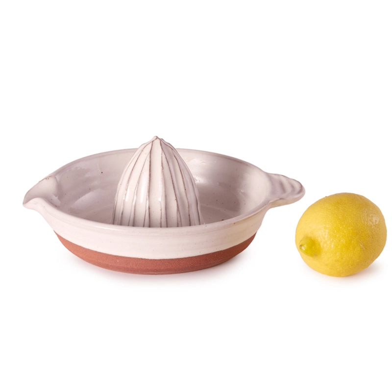 Perfect Hideaways: A handcrafted ceramic country citrus squeezer with a white glazed top and natural terracotta base, displayed beside a fresh lemon on a white background. Perfect Hideaways shop