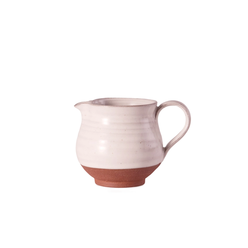 Perfect Hideaways: A handcrafted Country Milk Jug with a white glazed upper and exposed terracotta base, featuring a curved handle and subtle ribbed detailing. Perfect Hideaways shop.