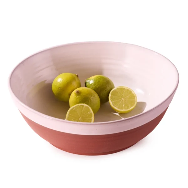 Perfect Hideaways: A terracotta and cream country serving bowl filled with whole and halved limes, styled with a minimalist aesthetic and natural lighting. Perfect Hideaways shop