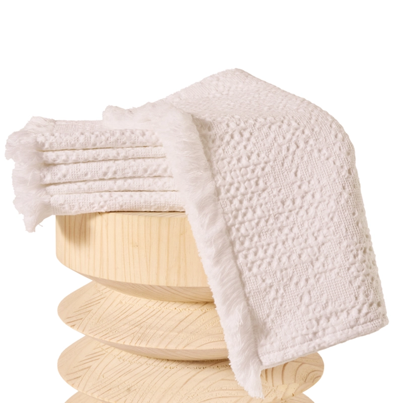 Perfect Hideaways: A neatly folded white textured bathmat with a woven waffle design and fringed edges, displayed on a carved wooden pedestal. Perfect Hideaways shop