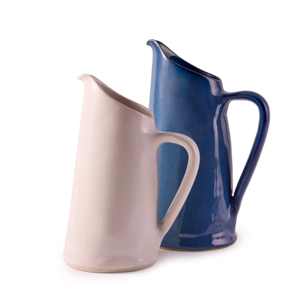 Perfect Hideaways: A pair of handcrafted ceramic water jugs, one in a glossy indigo blue and the other in a soft matte white, designed with elegant curves and sculptural form. The shop