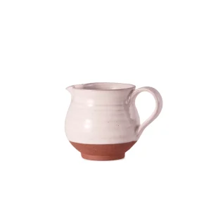 Perfect Hideaways: A side view of a small Country Milk Jug, showcasing its smooth white glaze, rounded body, and warm terracotta base with a gracefully arched handle. Perfect Hideaways shop.