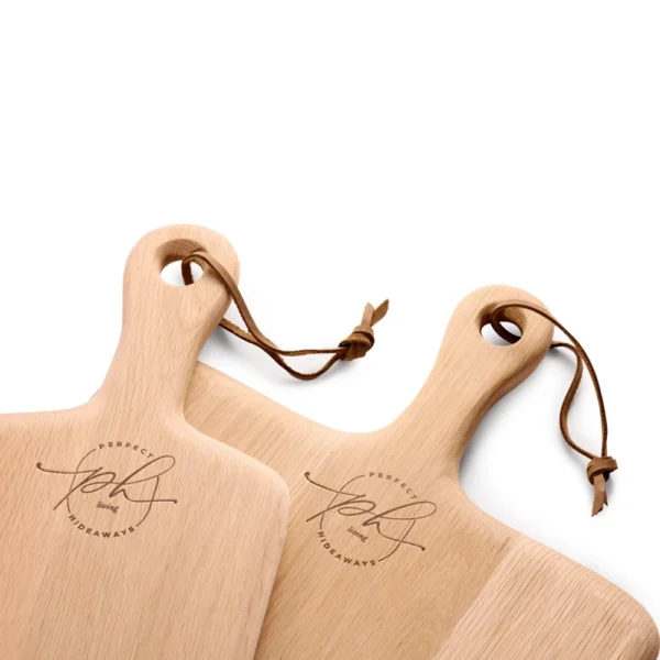 Perfect Hideaways: A close-up of two elegant Oak Rectangular Paddle serving boards featuring the Perfect Hideaways logo and leather ties, showcasing their refined craftsmanship. Perfect Hideaways shop