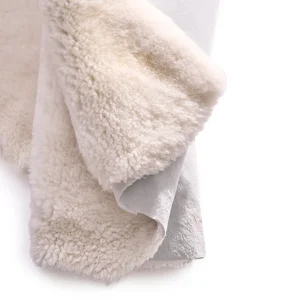 Perfect Hideaways: A close-up of a folded ivory sheepskin rug, highlighting the thick, fluffy fleece and suede-like underside. Perfect Hideaways shop
