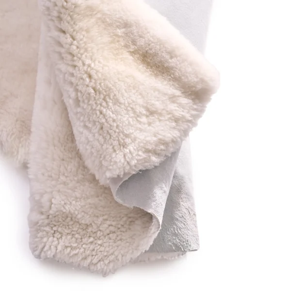 Perfect Hideaways: A close-up of a folded ivory sheepskin rug, highlighting the thick, fluffy fleece and suede-like underside. Perfect Hideaways shop