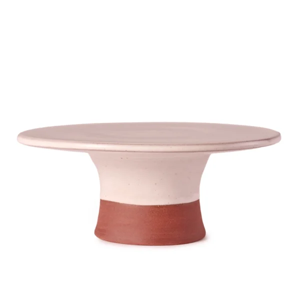 Perfect Hideaways: A side view of a contemporary country cake stand featuring a smooth blush surface and a curved terracotta base with a natural matte finish. Perfect Hideaways shop