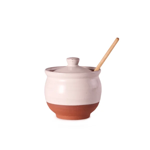 Perfect Hideaways: A side view of a lidded Country Sugar Bowl with a warm terracotta base and pale glaze, complete with a slender wooden spoon. Perfect Hideaways shop.