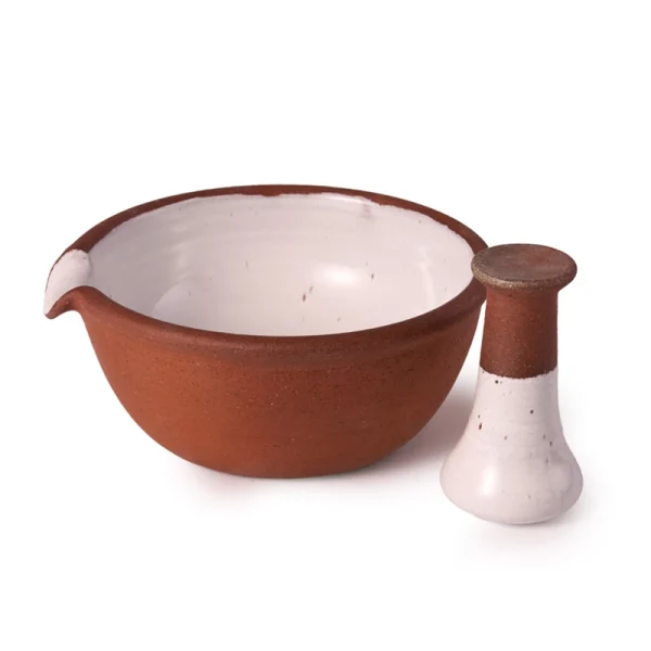 Perfect Hideaways: A ceramic mortar and pestle set with the pestle placed upright next to the bowl, highlighting the two-tone clay and glaze finish. The shop