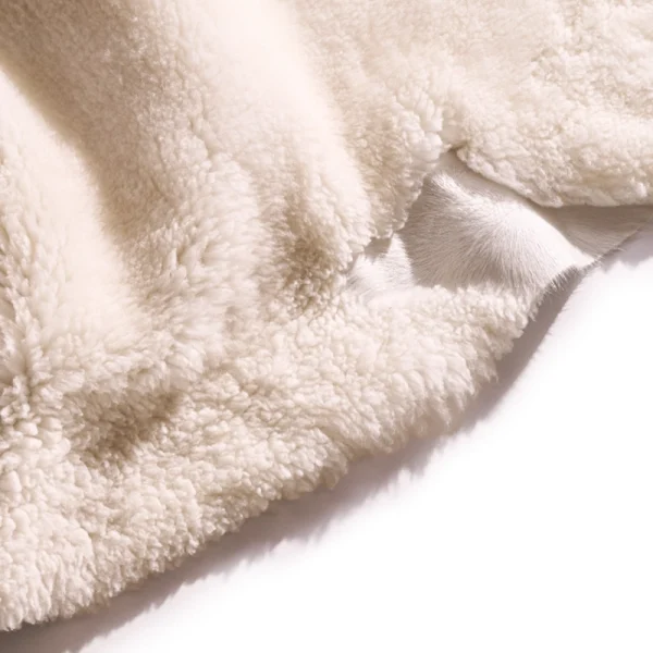 Perfect Hideaways: Detail view of the plush, cream-coloured wool fibres on a sheepskin rug, showing the natural hide underneath. Perfect Hideaways shop