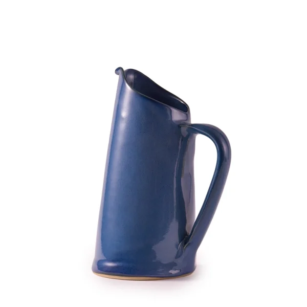 Perfect Hideaways: A side angle of the blue ceramic water jug by Mervyn Gers, highlighting its curved handle and high-gloss texture. The shop