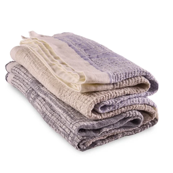 Perfect Hideaways: A neatly folded stack of three Ocean Bogolan Lounge Throw in harmonious shades of beige, cream, and lavender, highlighting their tactile detail and layered textures. Perfect Hideaways shop