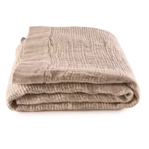 Perfect Hideaways: A neatly folded Sand Bogolan Bed Throw with a lightly quilted texture, showcasing its cosy and artisanal weave. Perfect Hideaways shop.