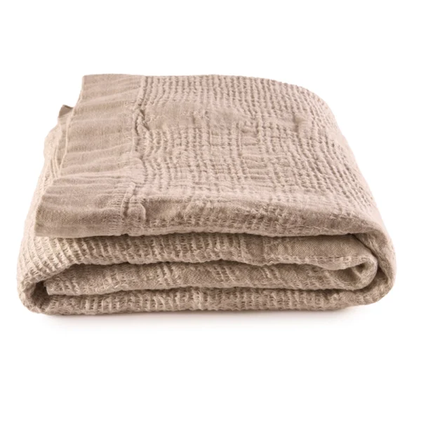 Perfect Hideaways: A neatly folded Sand Bogolan Bed Throw with a lightly quilted texture, showcasing its cosy and artisanal weave. Perfect Hideaways shop.