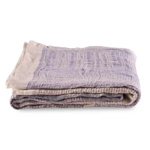 Perfect Hideaways: A single folded Ocean Bogolan Lounge Throw with a subtle lavender and beige pattern, revealing a finely woven texture and soft fabric finish. Perfect Hideaways shop