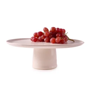 Perfect Hideaways: A bunch of fresh red grapes arranged on a smooth ceramic pedestal cake stand with a soft matte finish. The shop