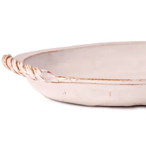 Perfect Hideaways: Close-up detail of a twisted rope-style handle on a classic baking dish with a weathered white glaze. The shop