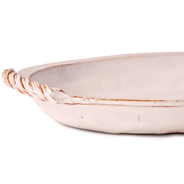 Perfect Hideaways: Close-up detail of a twisted rope-style handle on a classic baking dish with a weathered white glaze. The shop