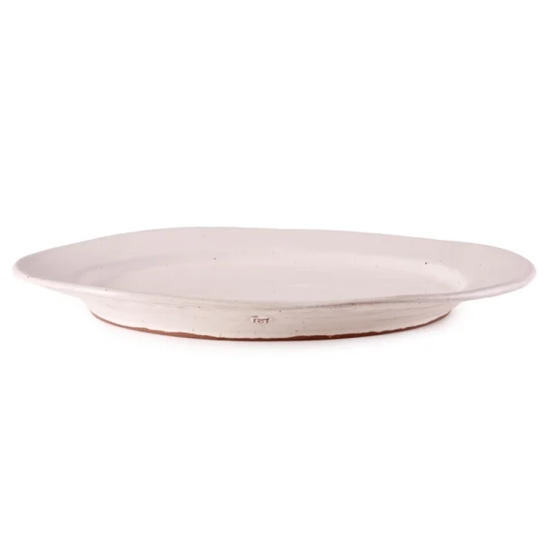 Perfect Hideaways: A large oval ceramic platter with an organic, slightly irregular rim and a natural off-white glaze, highlighting the handcrafted design and terracotta base. Perfect Hideaways shop.