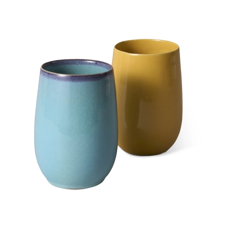 Perfect Hideaways set of two handcrafted ceramic tumblers, one in soft turquoise blue with a deep indigo rim and the other in warm mustard yellow, both with a smooth matte finish. Perfect hideaways shop.