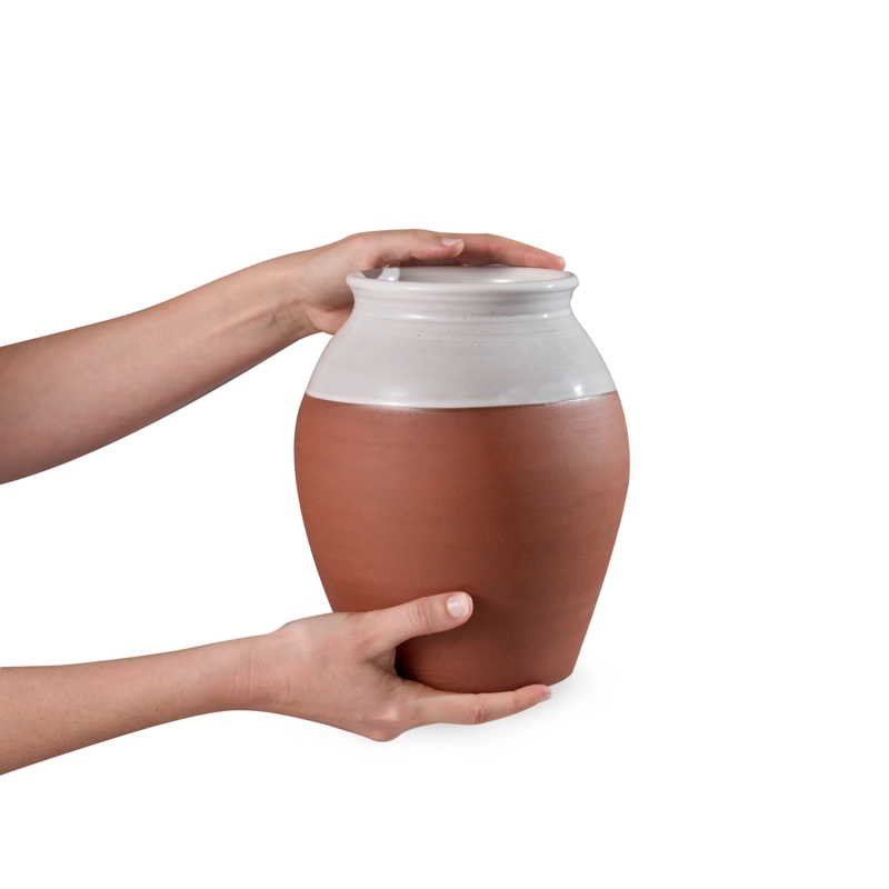 Perfect Hideaways handcrafted terracotta country vase being held in both hands, showing the smooth two-tone finish with a natural clay base and white glazed top. Perfect hideaways shop.